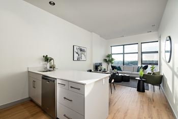 A modern kitchen with a dishwasher, sink, and a green chair.